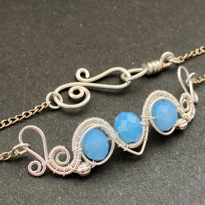 A silver-plated necklace with blue glass beads and decorative metalwork