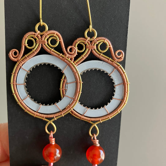 Decorative earrings with intricate designs on a black card