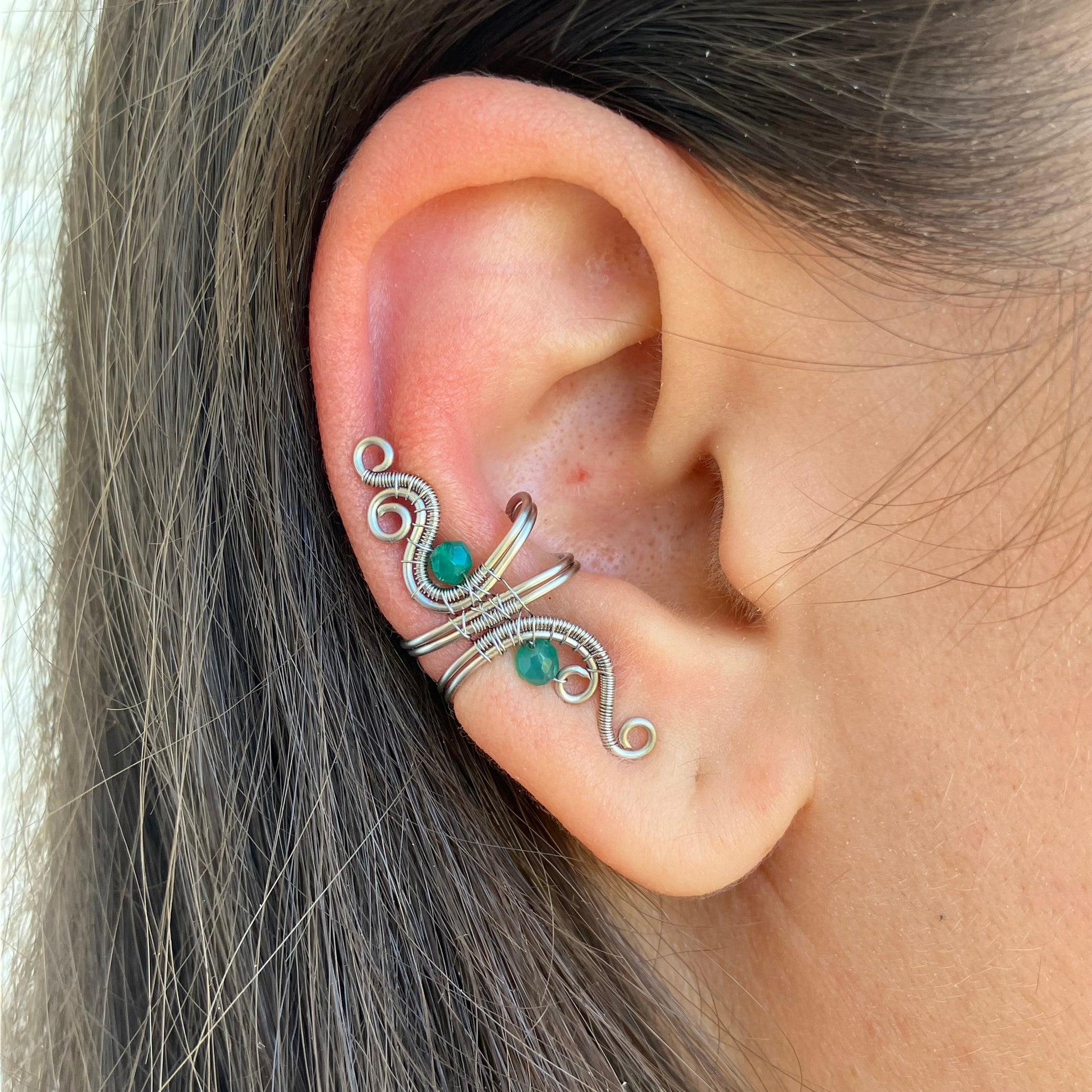 Close-up of an ear with a decorative silver and green onyx earring.
