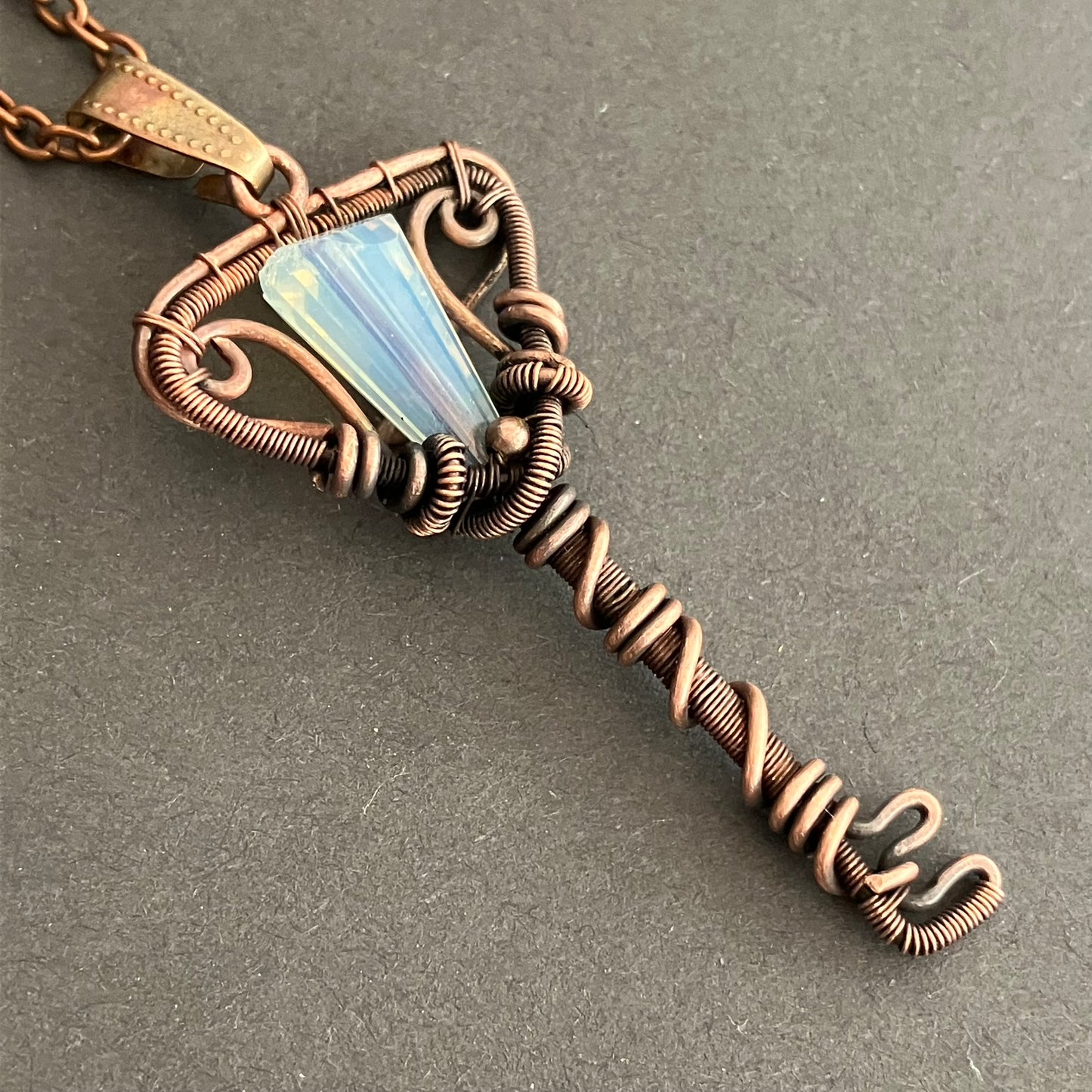 Copper wire key-shaped pendant with a opal glass bead