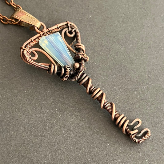 Copper wire key-shaped pendant with a opal glass bead