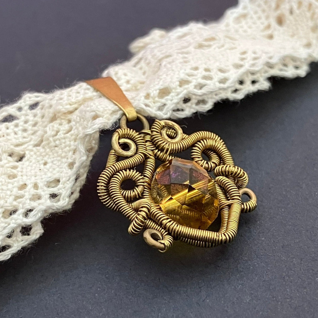 brass wire wrapped pendant with topaz colored glass bead on white lace choker