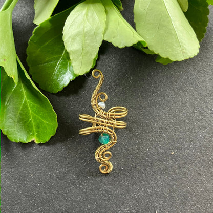 A brass ear cuff with wire wrapping, featuring a small pearl and a green onyx bead