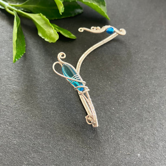 A silver-plated ear wrap with blue glass beads