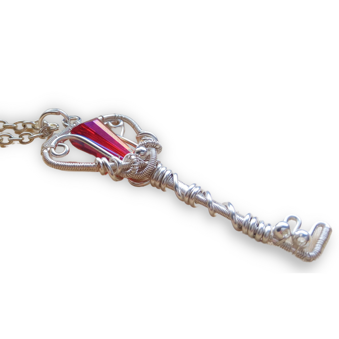 silver wire wrapped necklace with a key shaped pendant and red glass bead